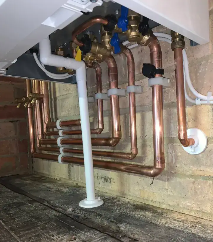 Copper pipework and plumbing installation beneath a boiler or heating system in a domestic property.