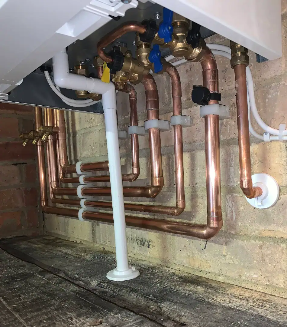Copper pipework and plumbing installation beneath a boiler or heating system in a domestic property.