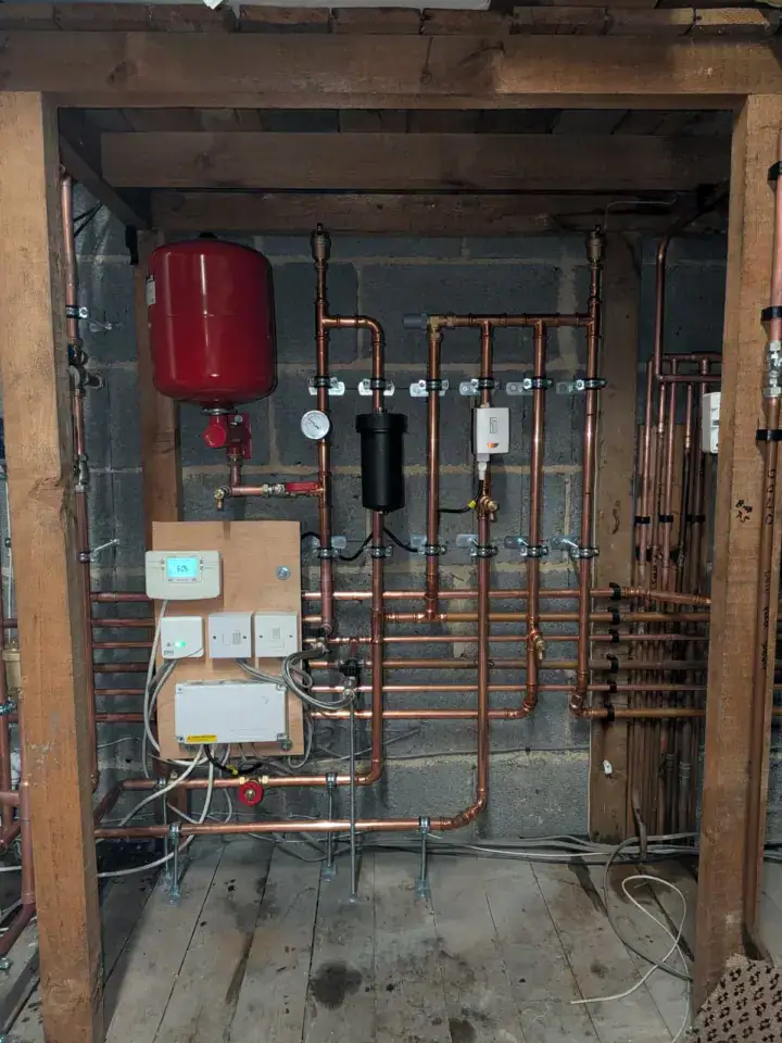 Copper pipework and a red expansion tank in a boiler installation at GM Heating Ltd, Leeds, Yorkshire.