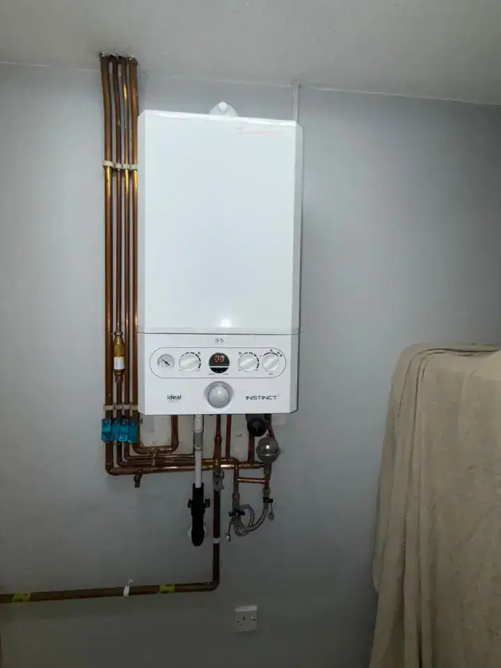 Modern wall-mounted boiler with copper pipes in a utility room, Leeds heating installation.