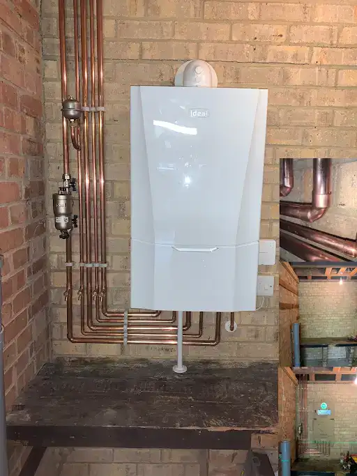 Modern wall-mounted boiler with copper pipes in a brick utility room, Leeds heating and plumbing installation.