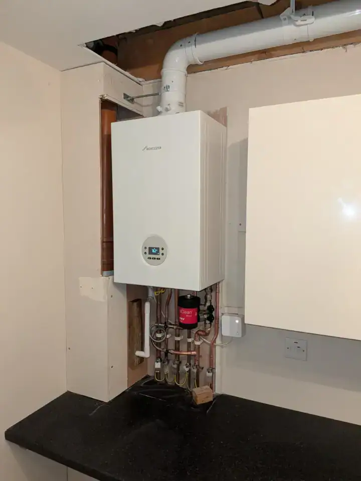 Gas boiler installed on wall with pipes and control panel in a utility room, Leeds, Yorkshire.